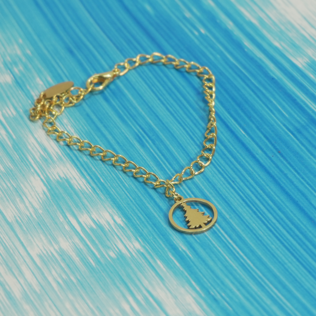 Pulseira Árvore de Natal Winter Magic dourada com pendente de árvore sobre fundo azul