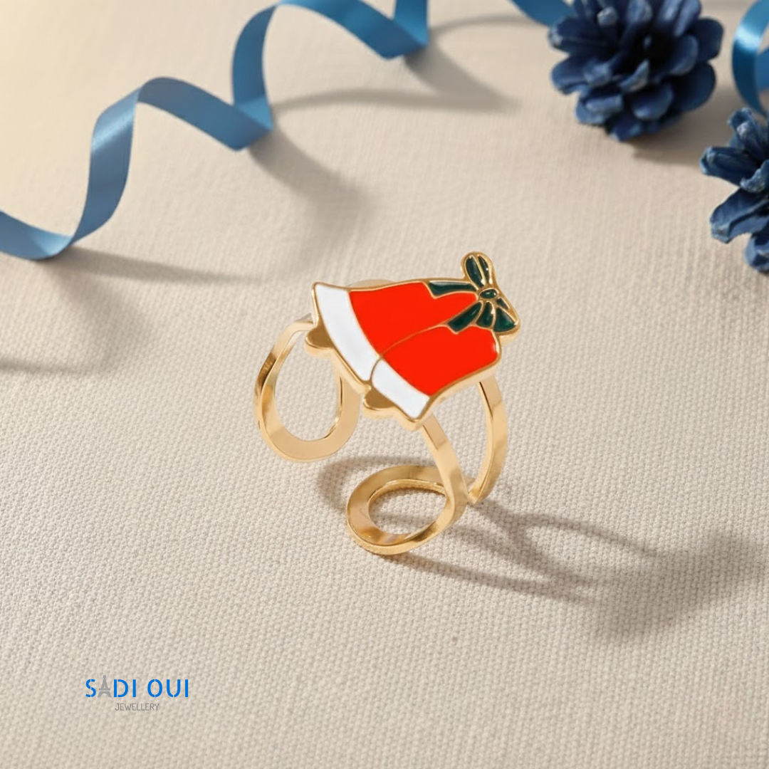 Anel Laço Vermelho Christmas Fun dourado com laço vermelho em fundo bege com fita azul e pinhas