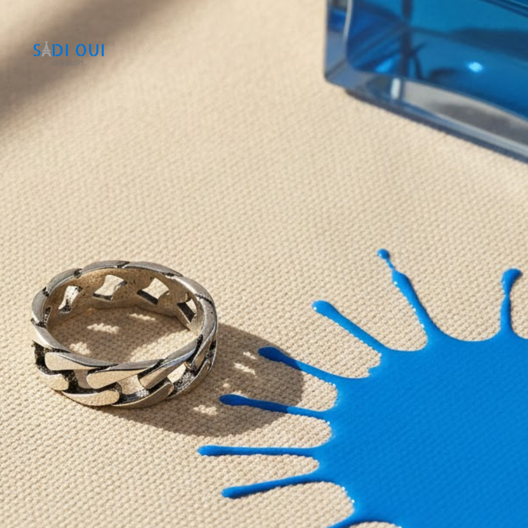 Anel Corrente Base em aço inoxidável prateado em fundo bege com mancha de líquido azul
