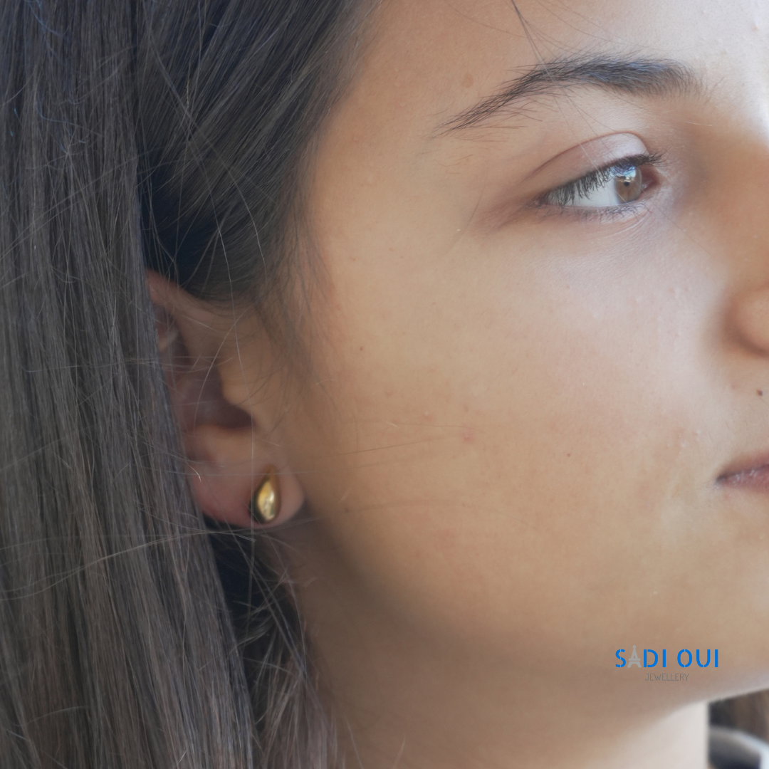 Brincos Pop Drop em aço inoxidável dourado na orelha de uma modelo
