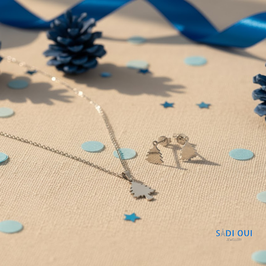 Conjunto Árvore de Natal Winter Magic com colar e brincos prateados sobre fundo bege com detalhes azuis, joias de Natal SADI OUI Jewellery
