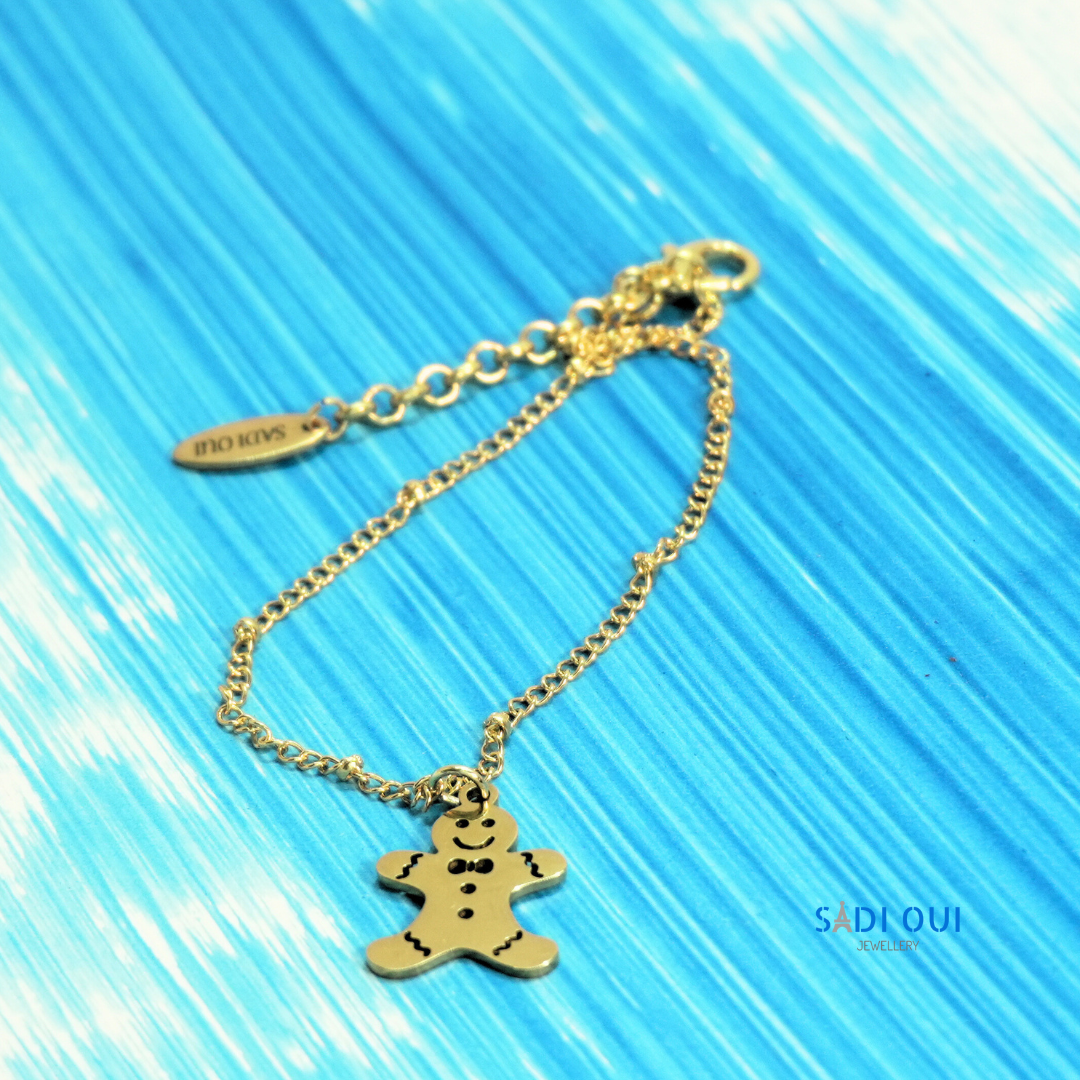 Pulseira Gingerbread Winter Magic dourada com pendente de boneco de gengibre em fundo azul
