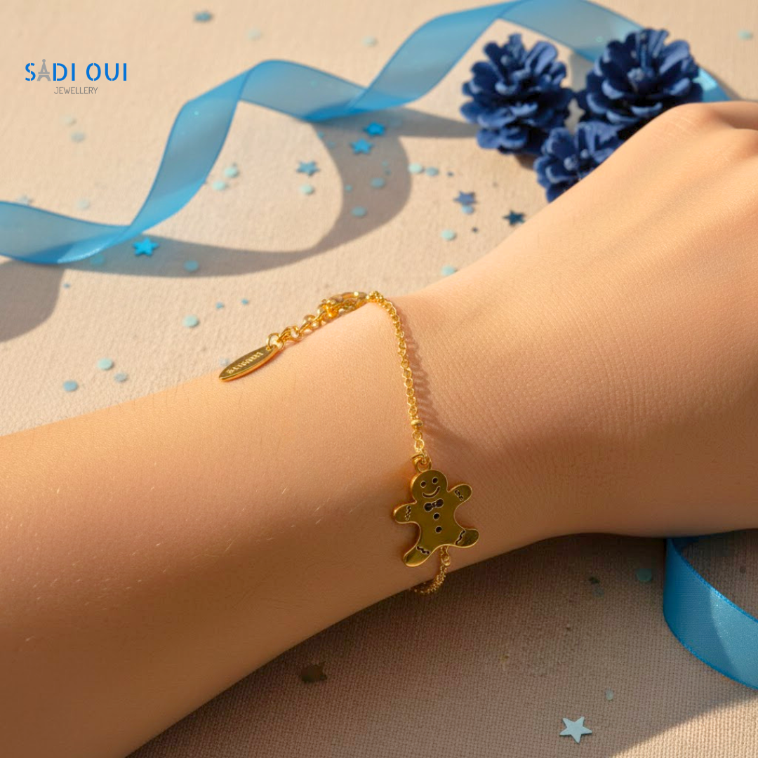 Pulseira Gingerbread Winter Magic dourada com pendente de boneco de gengibre no pulso de uma pessoa
