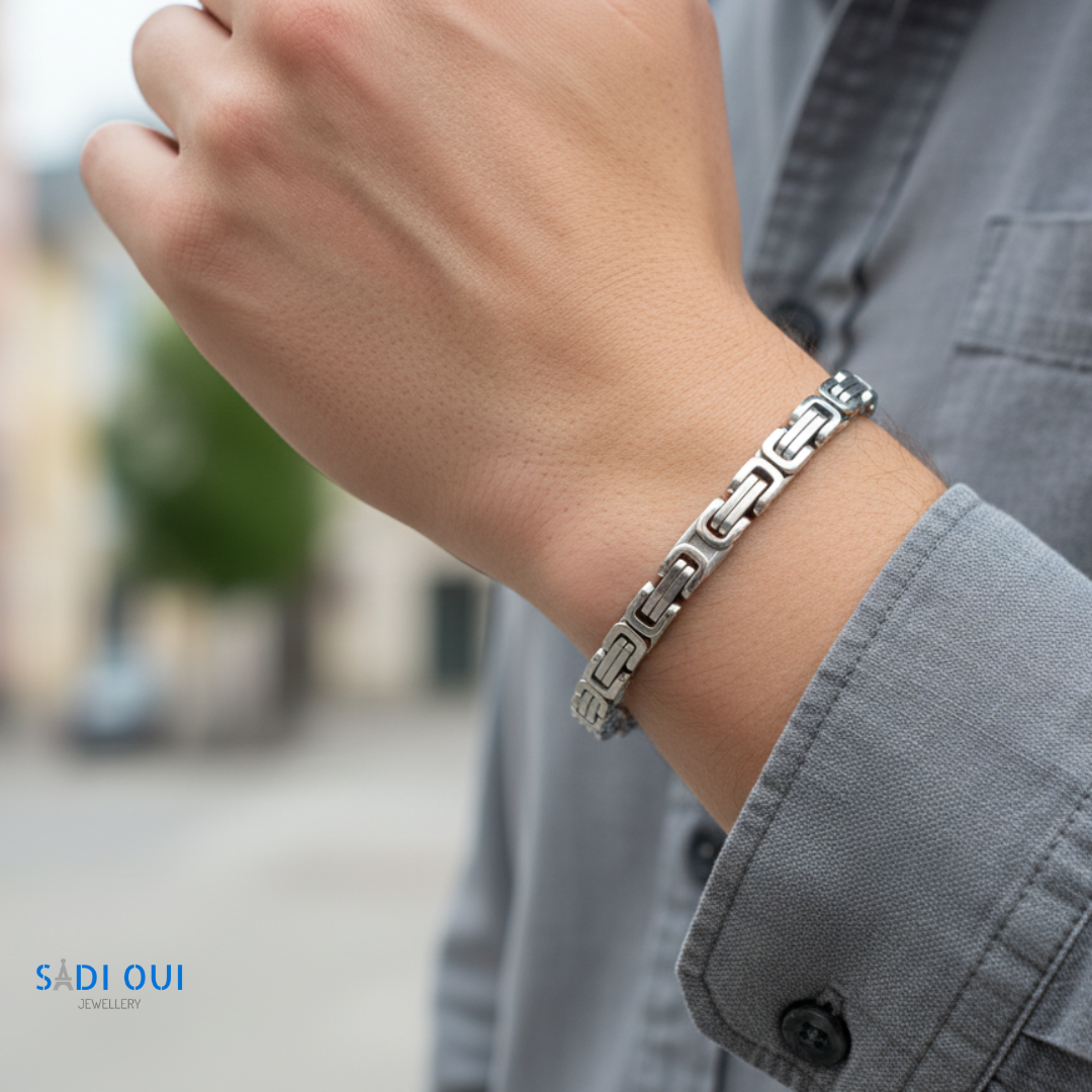 Pulseira Masculina Base em aço inoxidável prateado no pulso de uma pessoa em ambiente de rua
